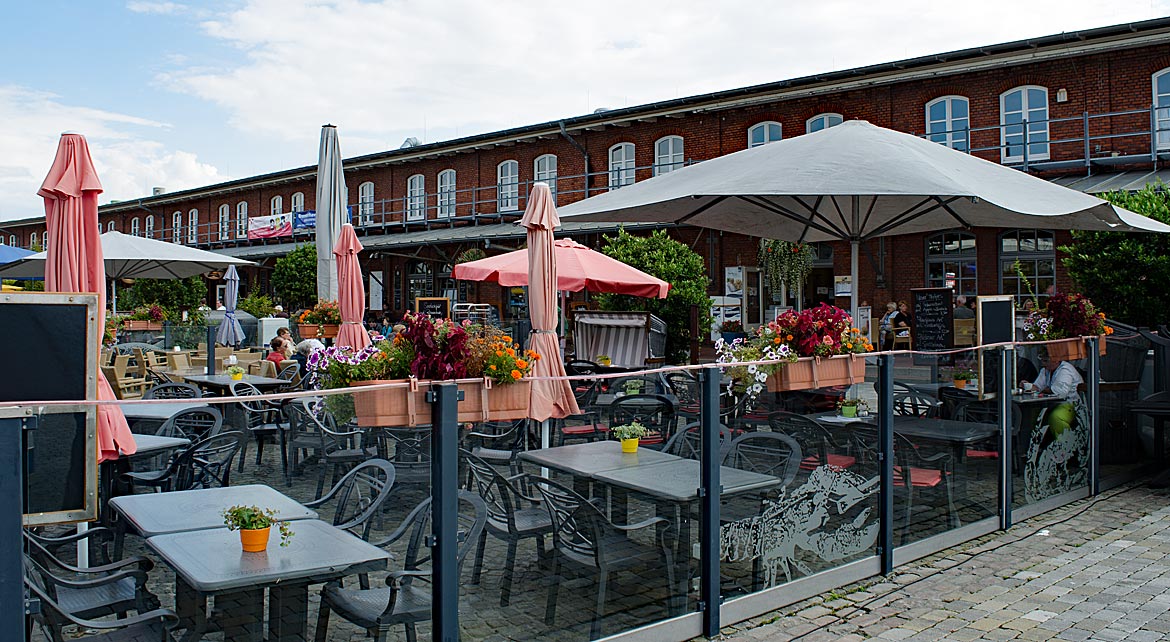 Freiluftbereich eines Restaurants im Schaufenster Fischereihafen, dahinter die restaurierte Fisch-Packhalle IV Schaufenster Fischereihafen in Bremerhaven